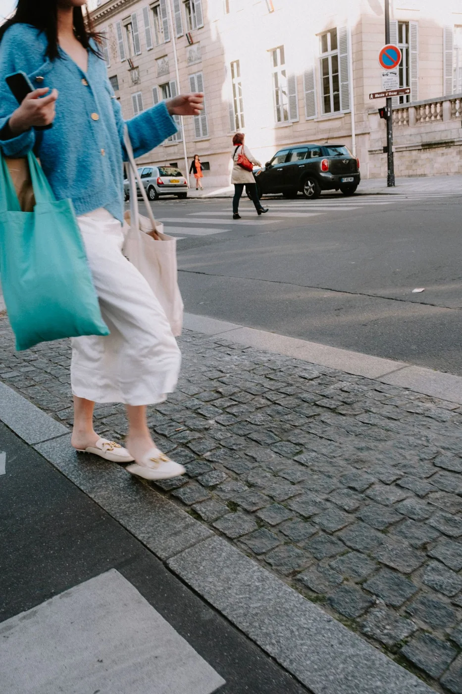Woman walking on a cobbled street carrying tote bags