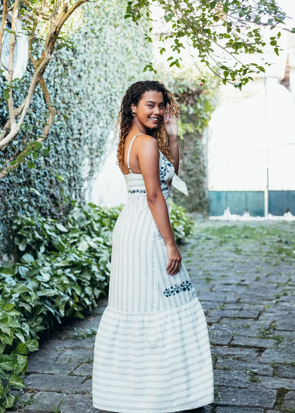 Woman wearing a light floral summer dress on a garden path