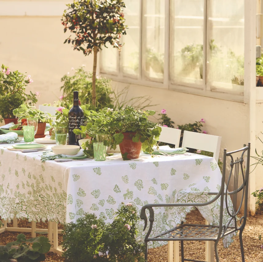 Botanical-patterned crockery and green accents arranged on a dining table