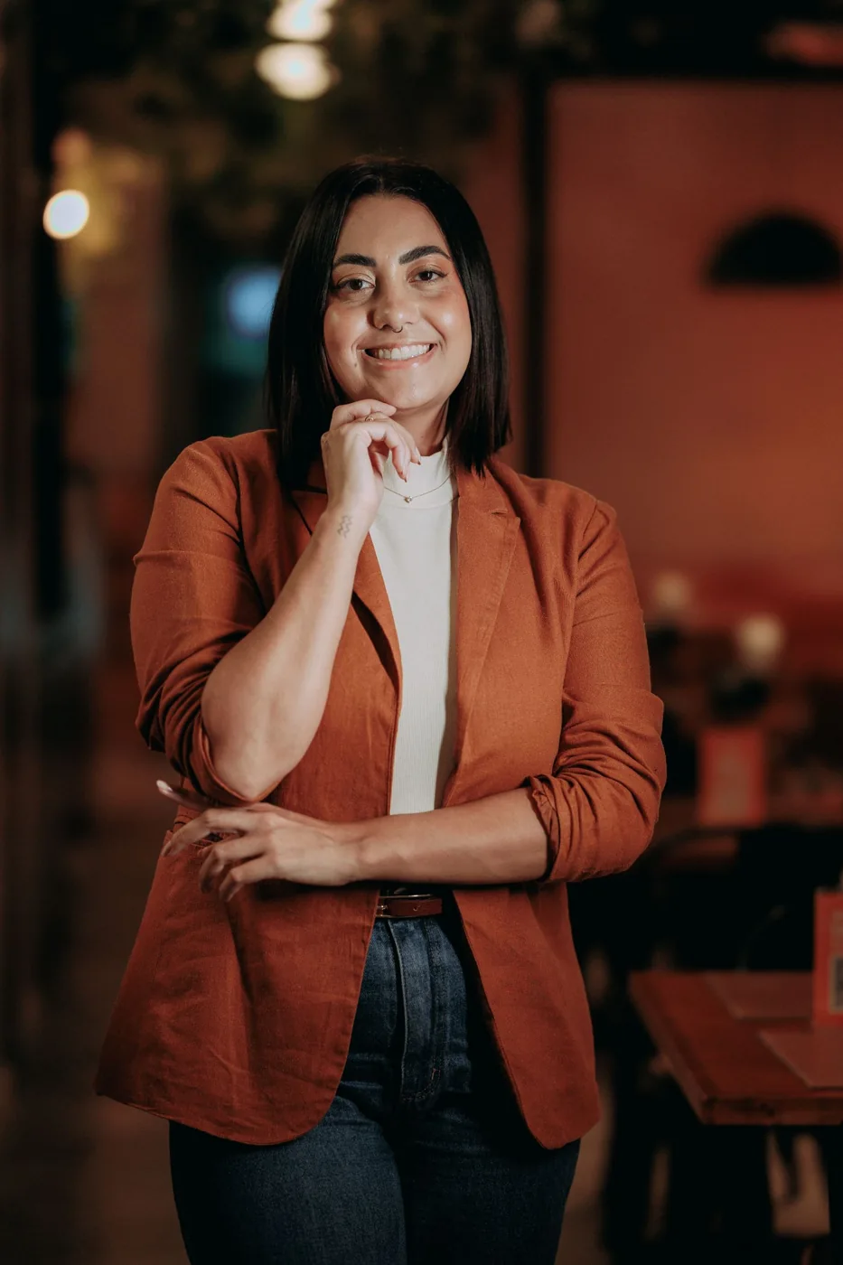 Woman in an orange blazer seated in a cafe
