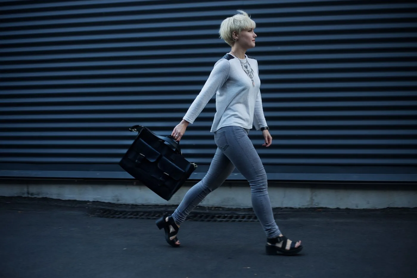 Woman walking along a city street carrying a black leather handbag