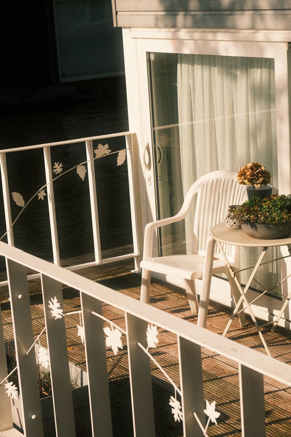 Small sunny balcony with a white chair and potted plants