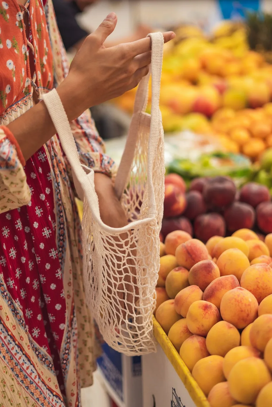 Reusable shopping bag beside fresh fruit at a market stall