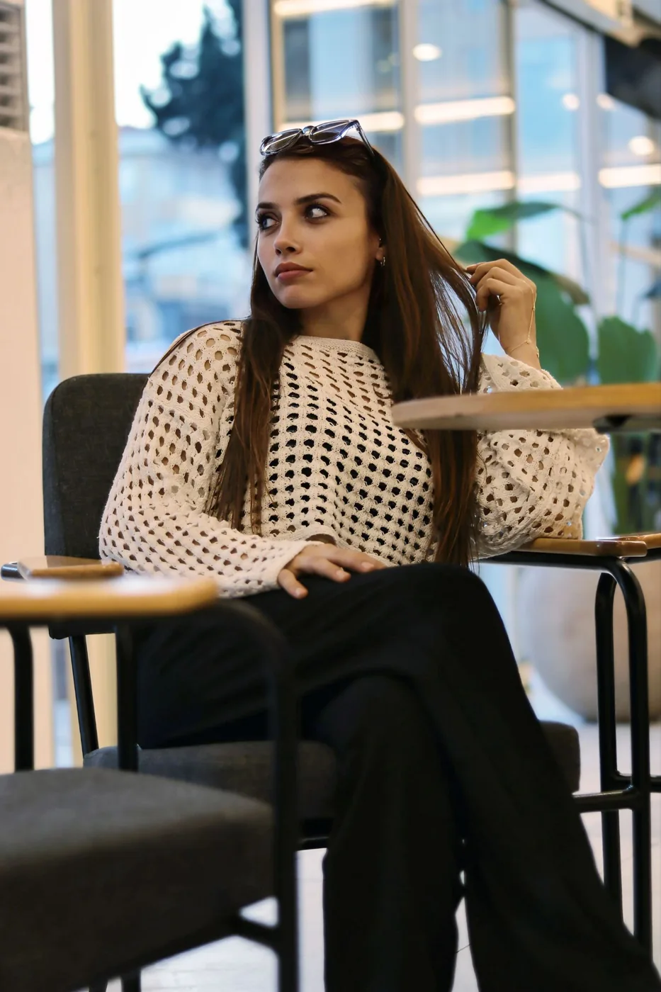 Woman in a white sweater and black trousers seated in a cafe