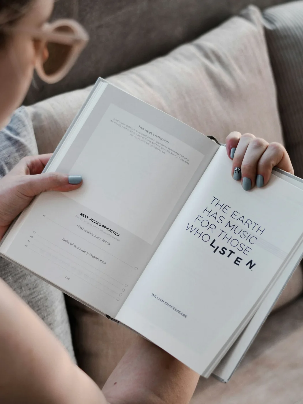Hands holding an open book above pale trousers.