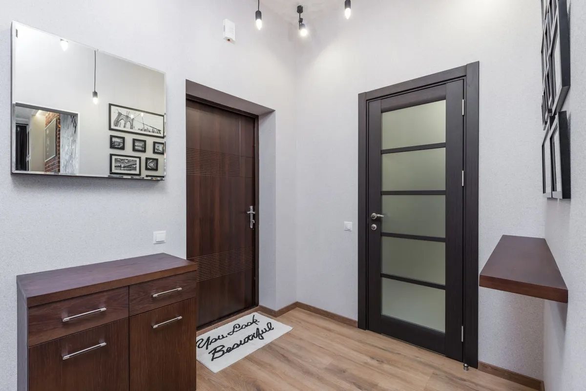 Entryway with framed pictures, a cabinet and a dark-framed interior door.