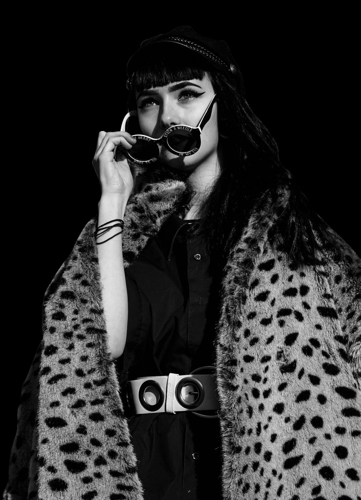 Black-and-white portrait of a woman wearing a leopard-print coat, hat and sunglasses.
