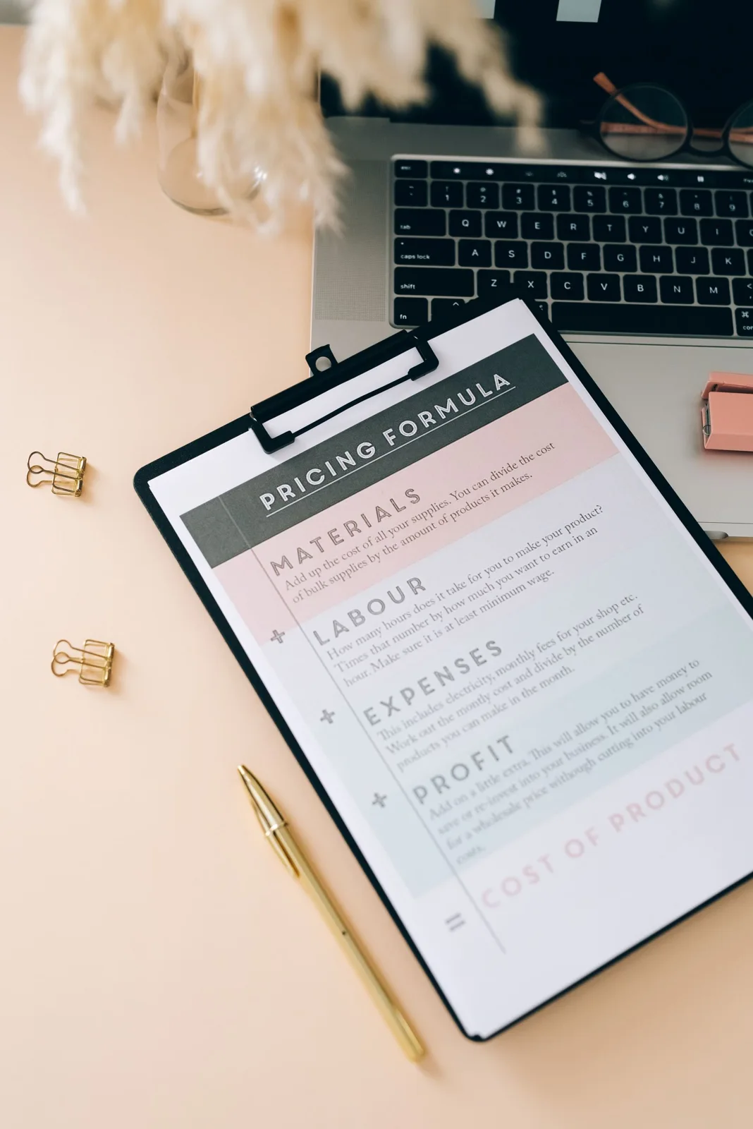 Clipboard holding a printed worksheet beside a laptop on a desk.