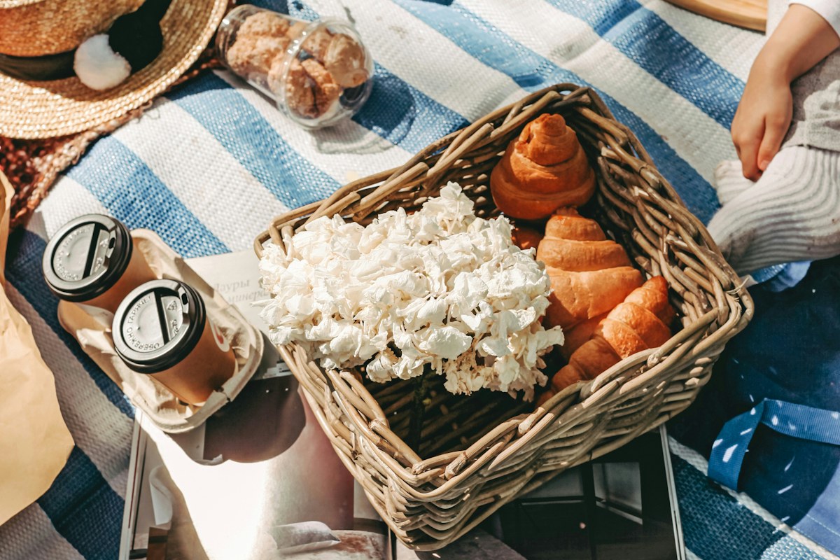 A basket of bread and popcorn on a blue-and-white striped picnic blanket.
