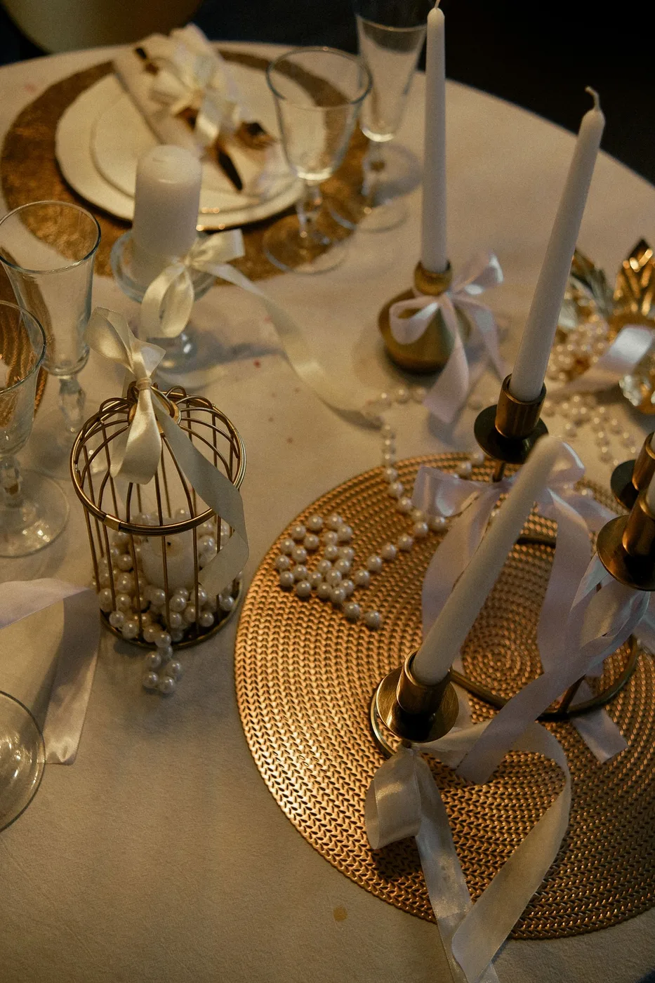 Ribbon, glassware and candles arranged on a decorated dining table.