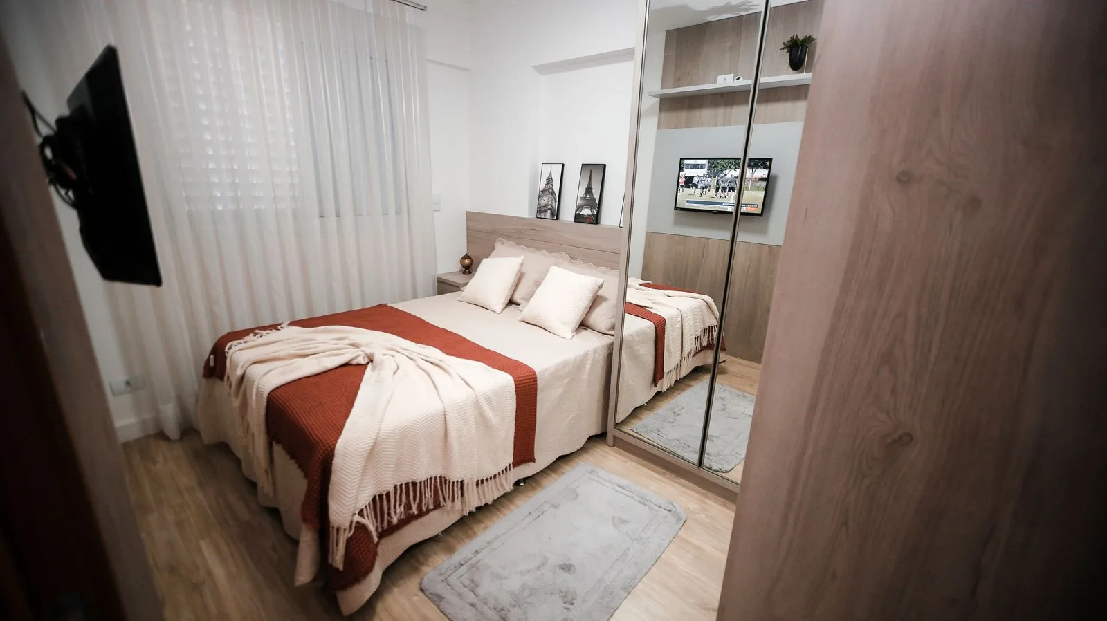 A neutral bedroom with layered bed linen, a bedside light and wooden furniture.