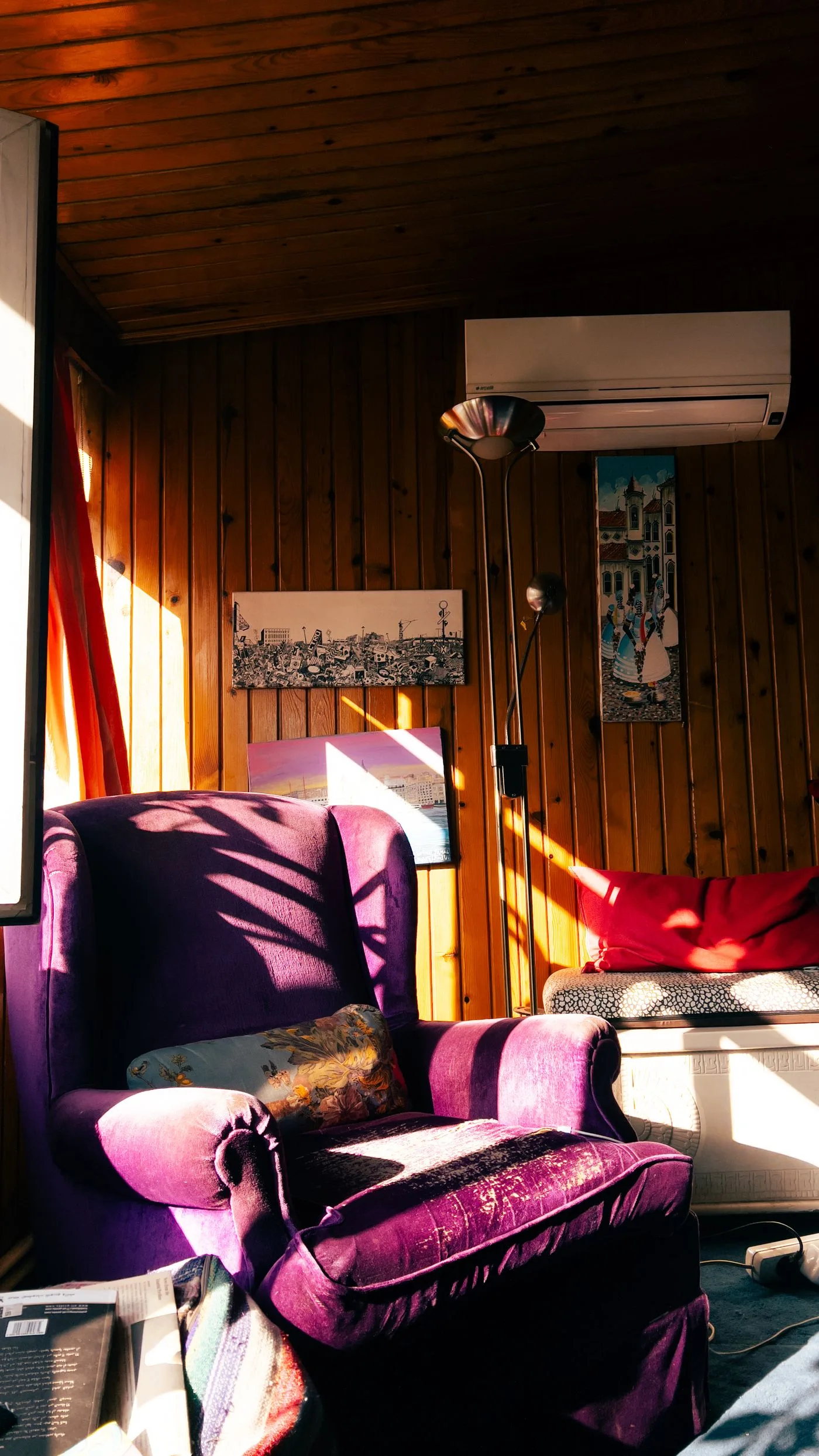 A sunlit wood-panelled room with a vivid purple chair and curtains.