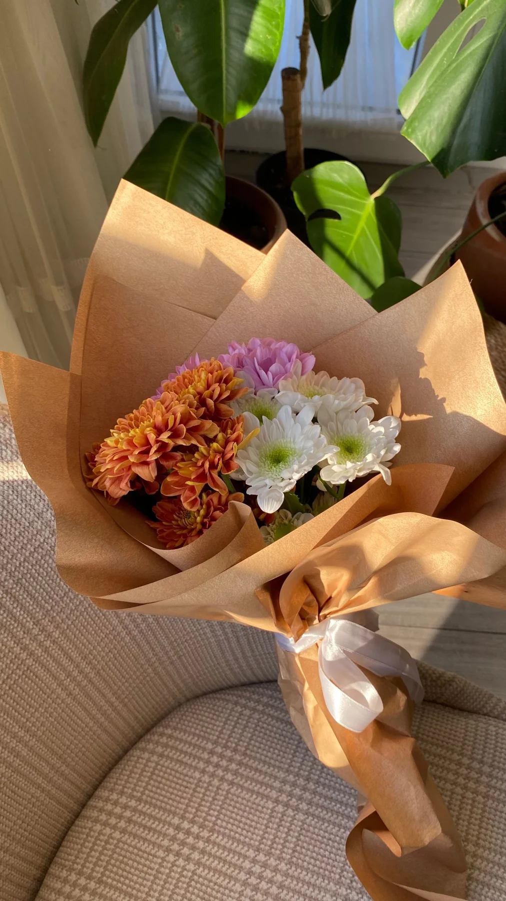 Flowers wrapped in brown paper with other wrapped stems behind them.