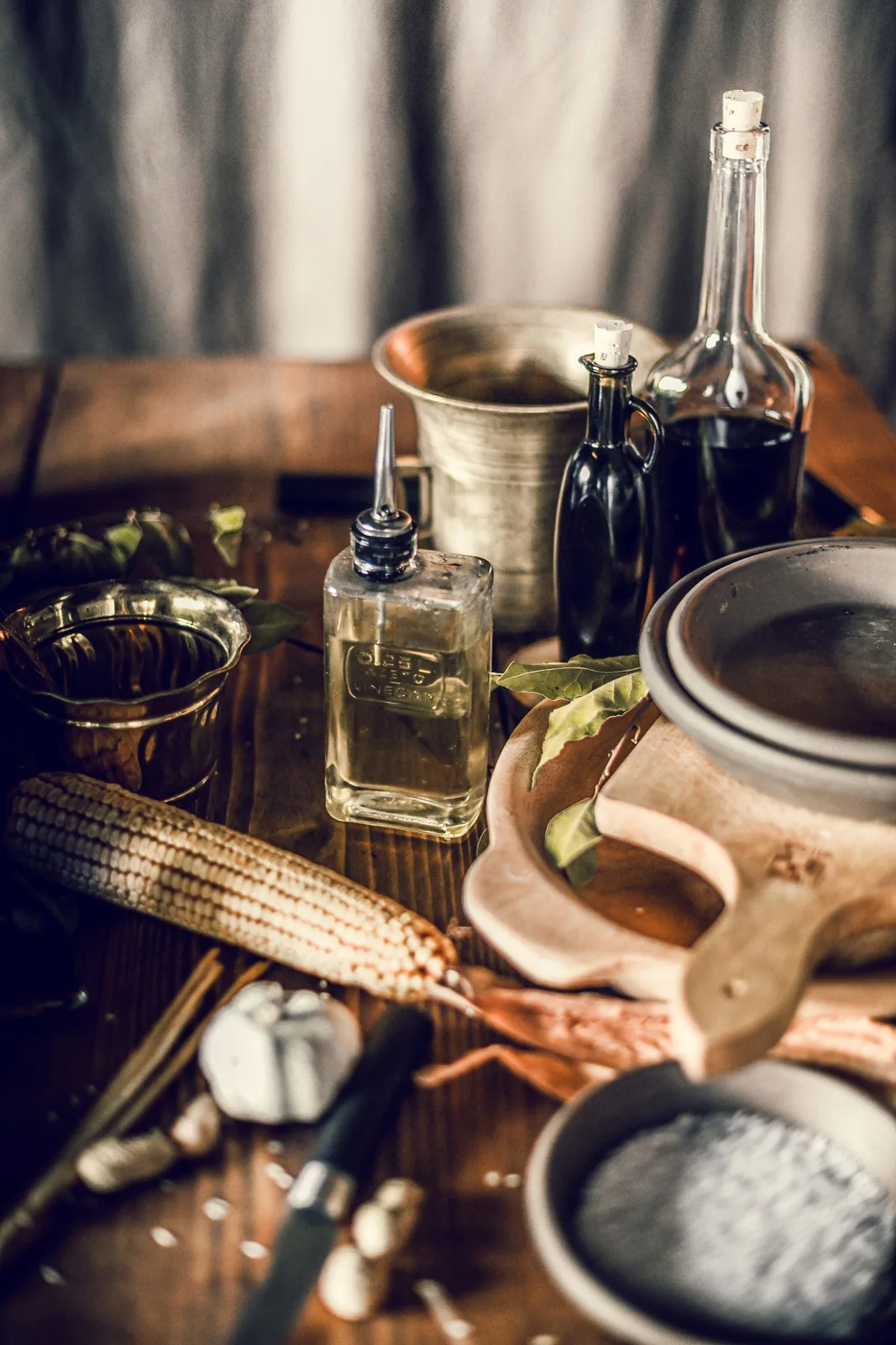 Bottles, cups and utensils arranged on a wooden table.