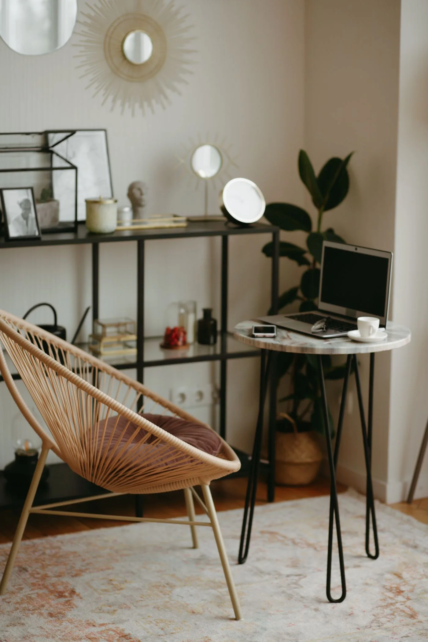 A narrow desk with a lamp and chairs beside a mirror and houseplants.