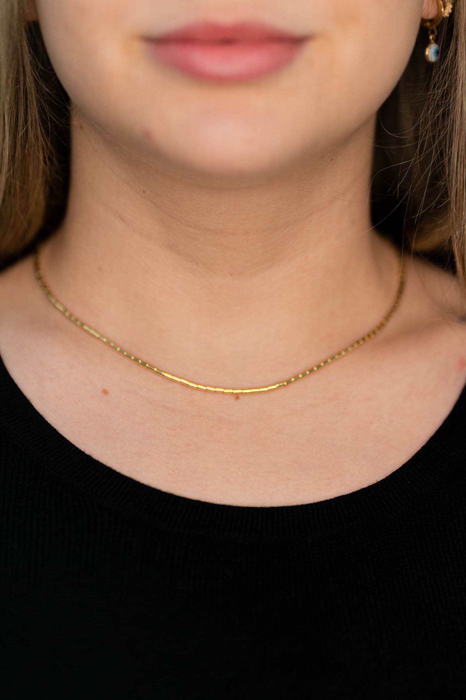 Close-up of a gold-coloured necklace worn with a black top.