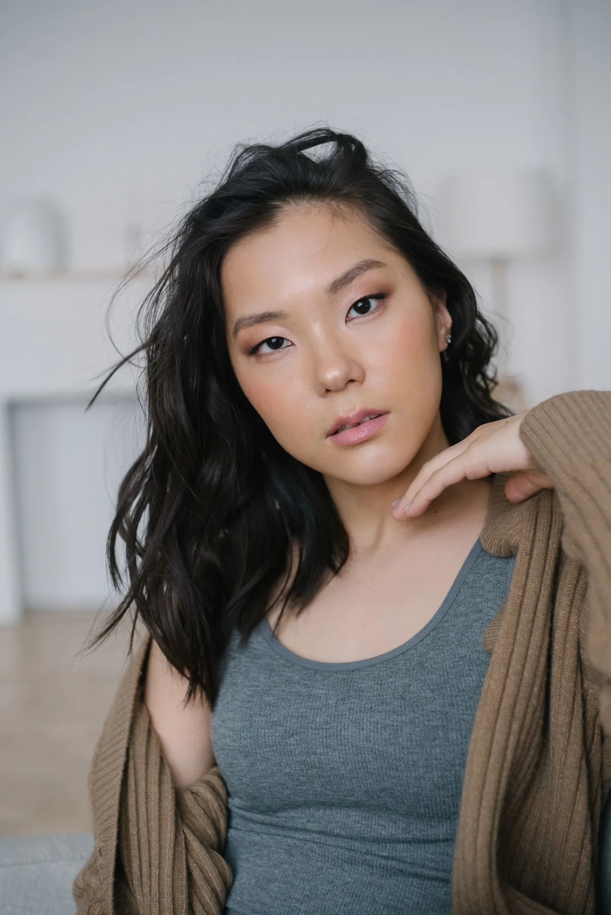 Woman wearing an open brown cardigan over a grey tank top.