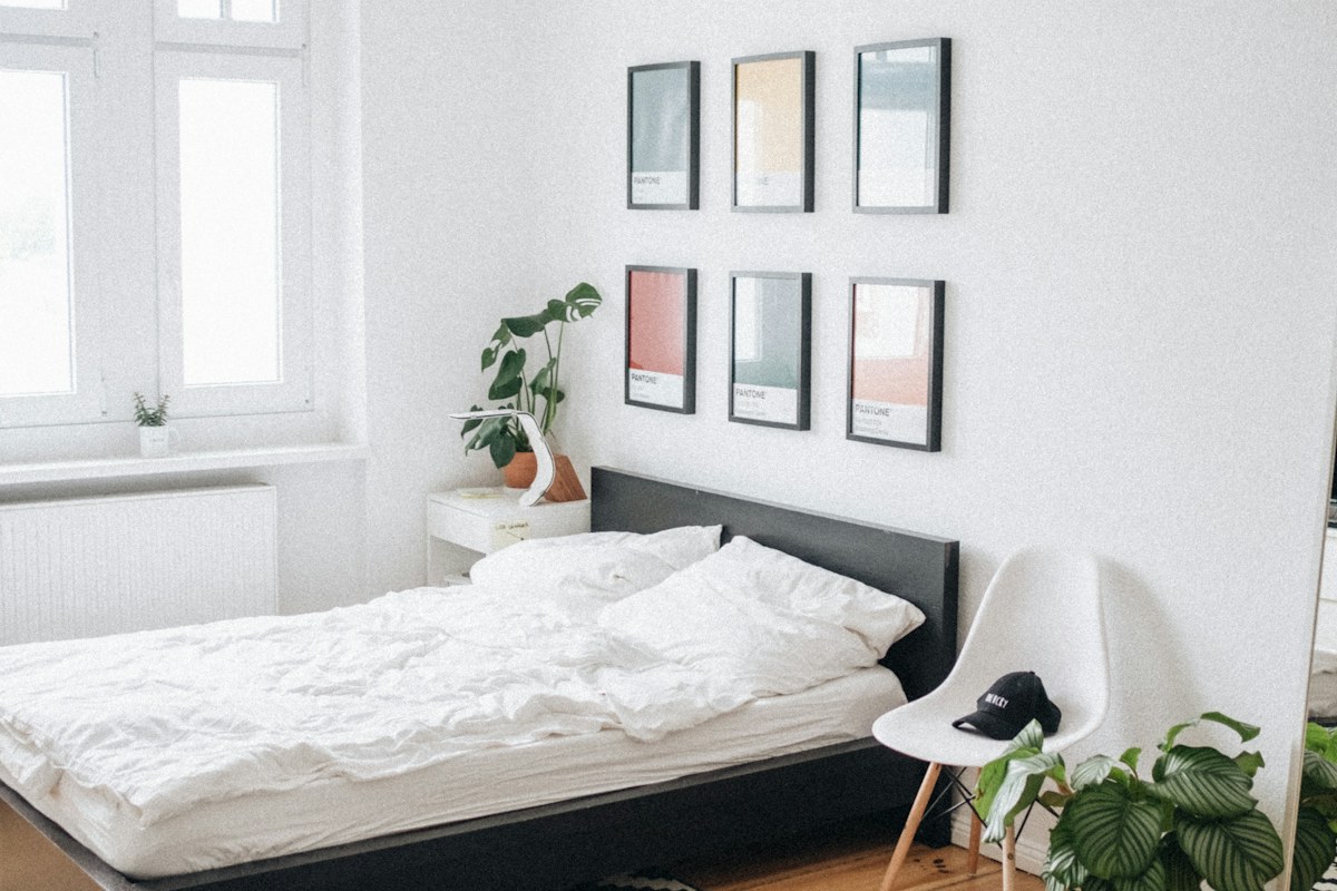 A dark bed frame with white bedding in a bright bedroom.