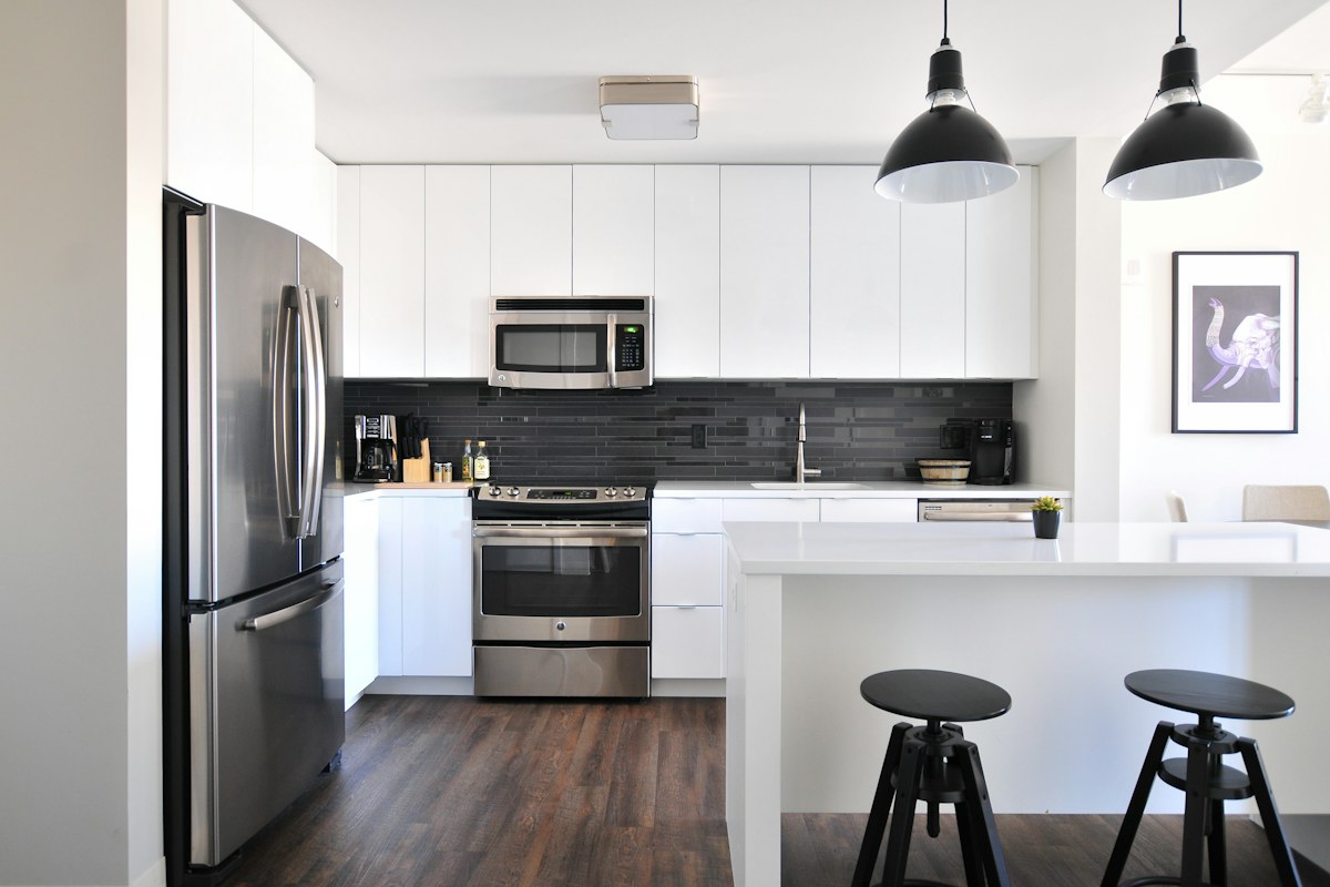 A refrigerator beside white cabinets in a compact kitchen.