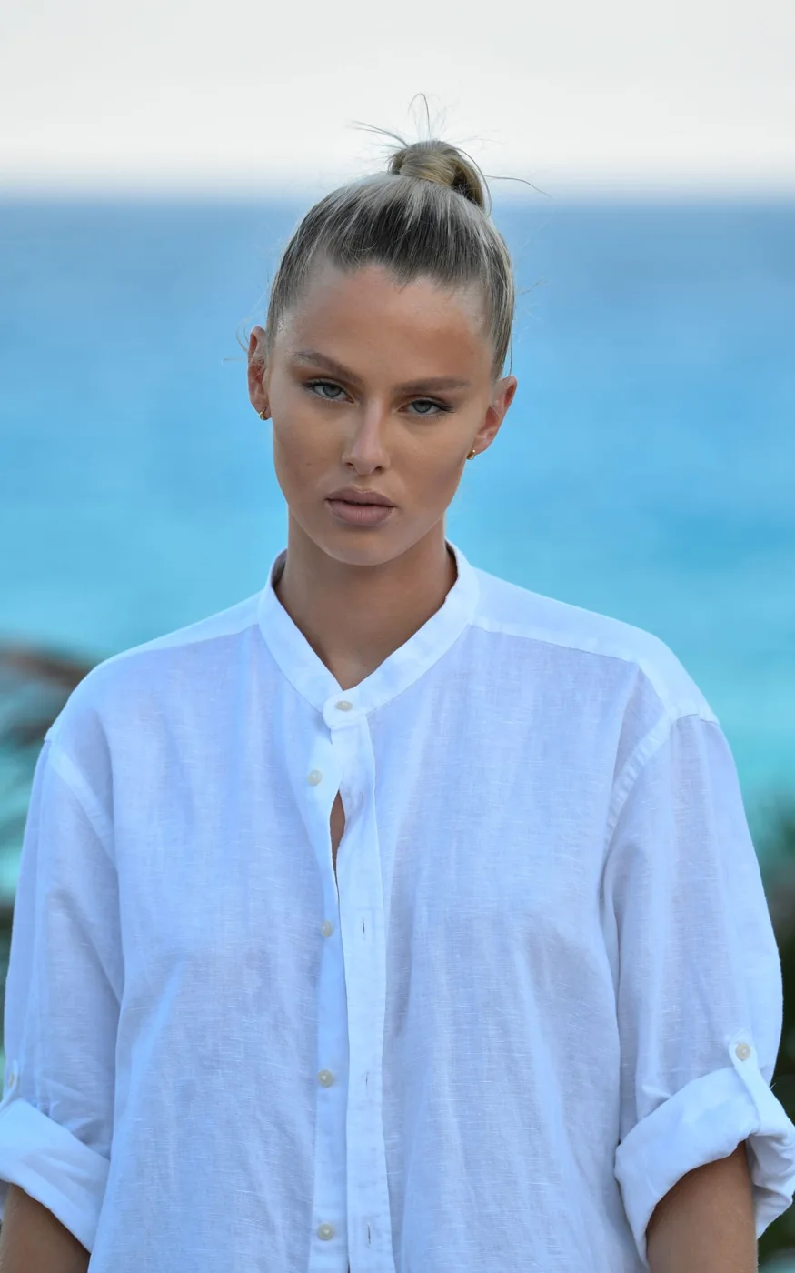 Woman wearing a white linen shirt beside the sea