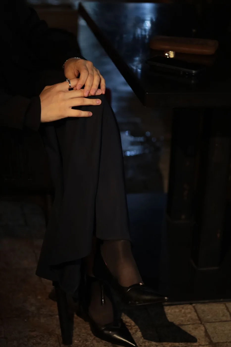 Woman wearing black evening separates in a dim indoor setting